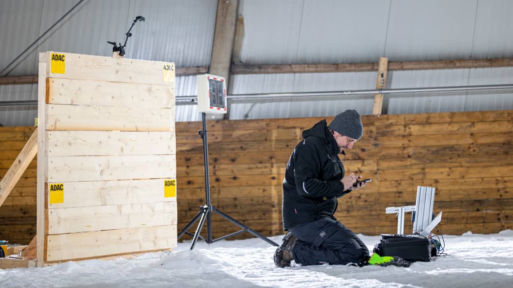 Ein Techniker kniet im Schnee wärend des ADAC Schlittencrashtest in der Skihalle in Bottrop