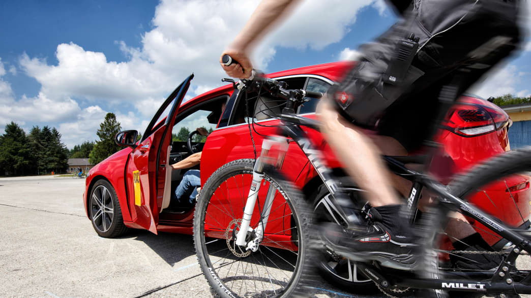 Fahrradfahrer fährt an ein Auto zum Test der Ausstiegswarnung