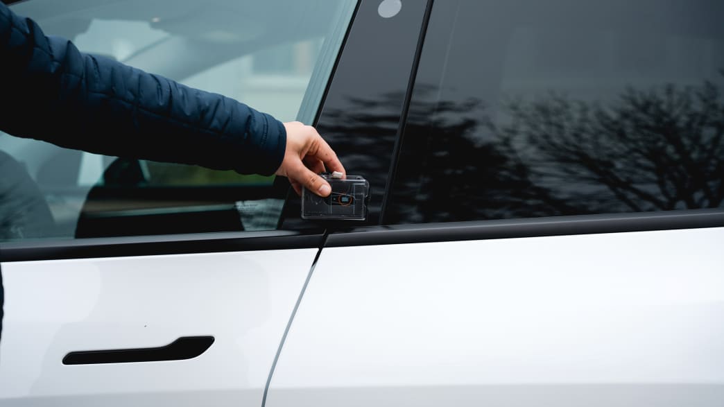 Hand hält Karte an den Türrahmen des Elektro-SUV Tesla Model Y um die Tür zu öffnen