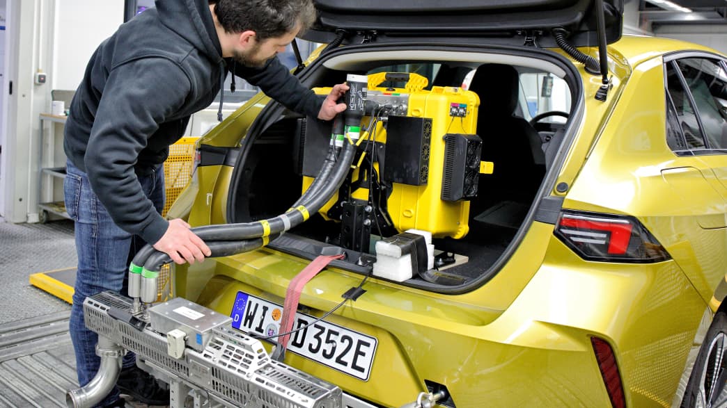 Ein Mitarbeiter aus Landsberg installiert Technik im Kofferraum eines Opels beim Eco Test 2023 im ADAC Technik Zentrum Landsberg