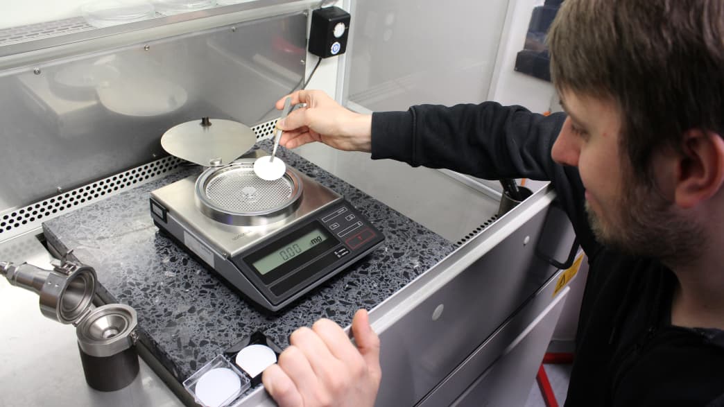 Ein Mitarbeiter aus Landsberg wiegt die Feinstaubpartikel beim Eco Test 2023 imADAC Technik Zentrum Landsberg