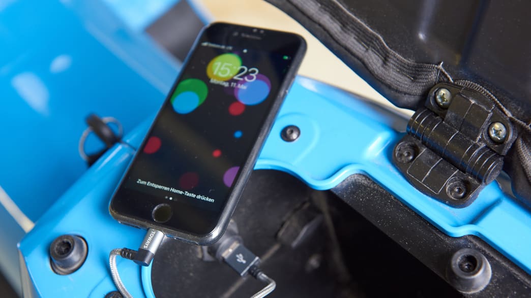 Ein Smartphone wird der Sattelbox des Elektroroller Schwalbe Govecs geladen