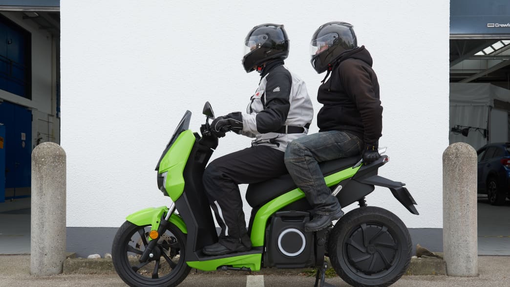 Der Elektroroller Silence S01 in schwarz-neongrün beim Test des Hauptständers, mit zwei Personen darauf
