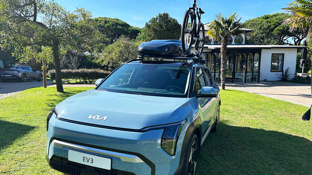 Der Kia EV3 mit Dachkoffer und Fahrrad auf dem Dach