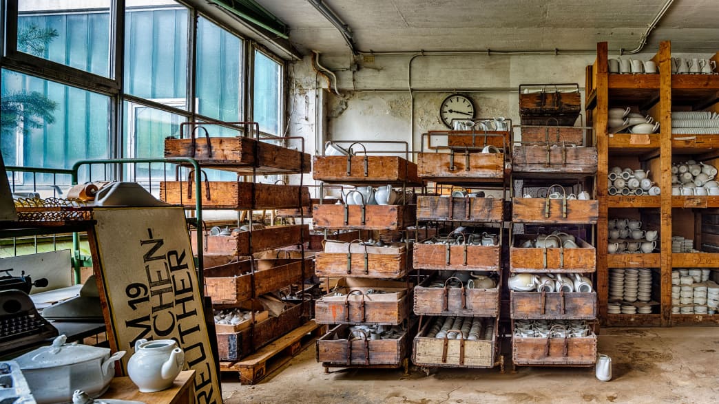 Holzregale mit Porzellan in einer verlassenen Porzellanfabrik
