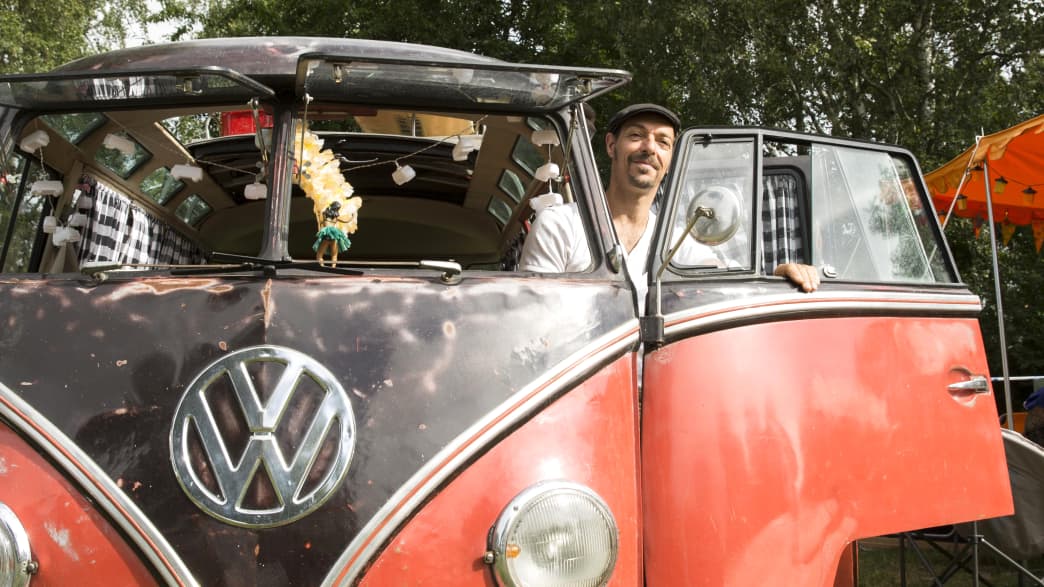 Mann steigt in seinen VW Bulli ein