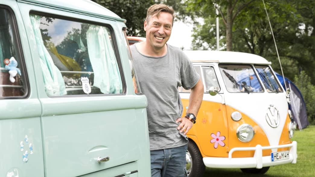 Mann steht an seinem VW Bulli