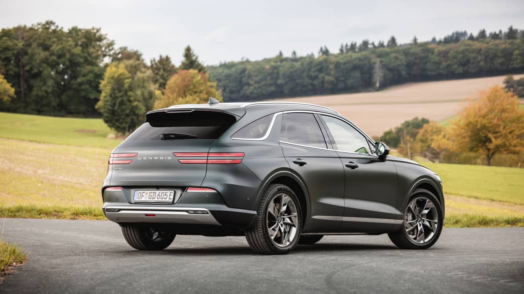 Standbild des Genesis Electrified GV70 schräg von hinten.