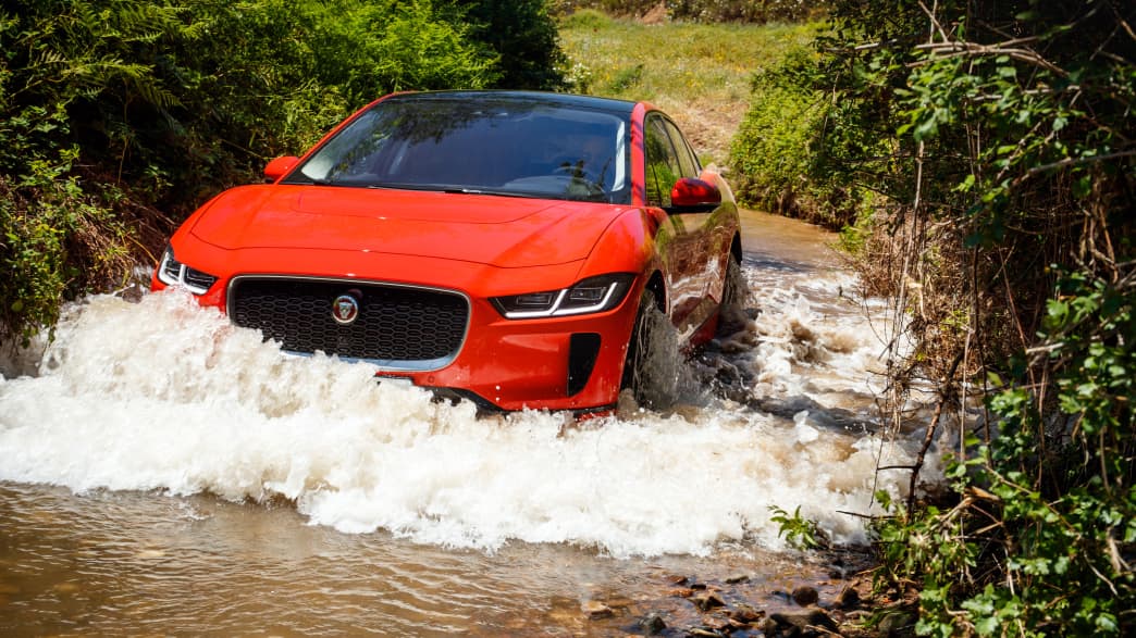 Roter Jaguar I-Pace faehrt durch Gelaende