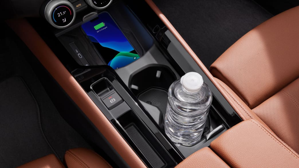 Eine Flasche steht in der Halterung eines Skoda Superb und ein Handy lädt in der Ladeschale