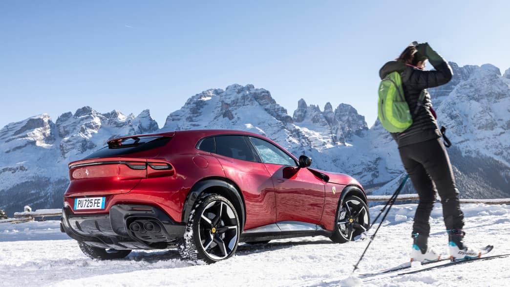 Ein roter Ferrari Purosangue vor verschneiter Bergkulisse
