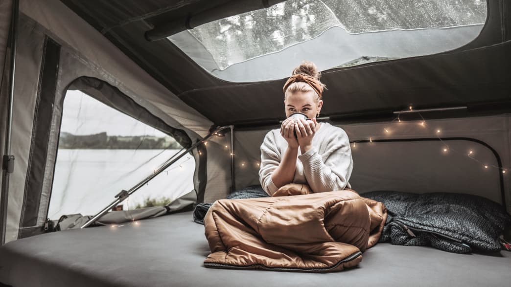 Eine Frau auf der Schlafmatratze im Innenraum des Campwerk Economy Faltcaravan