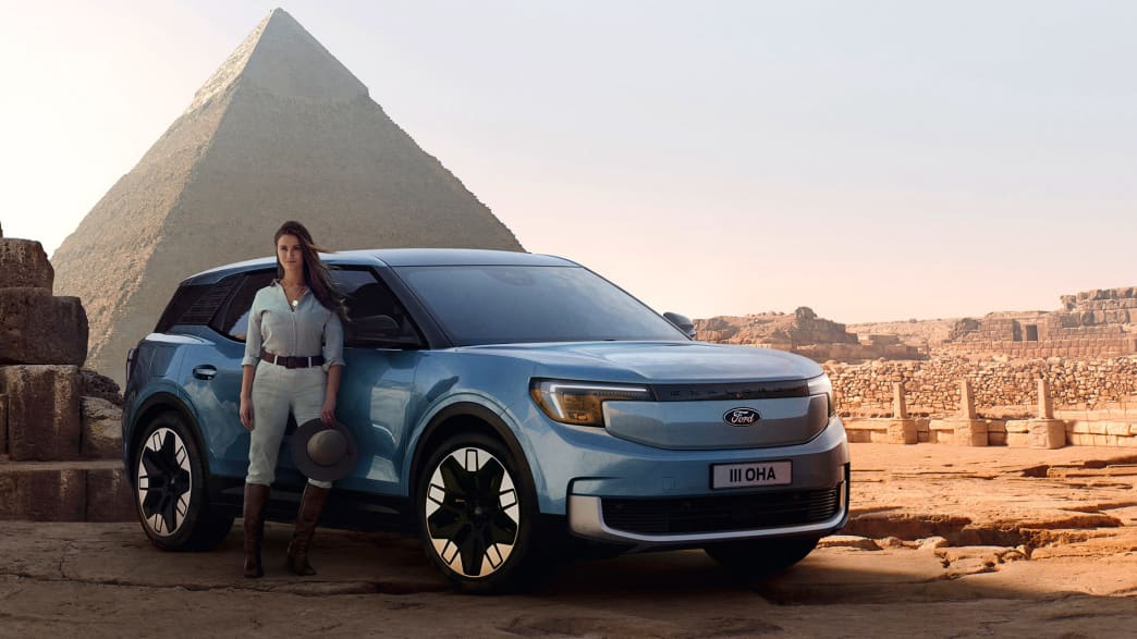 Eine Frau lehnt an einen Ford Explorer der vor der großen Pyramide steht
