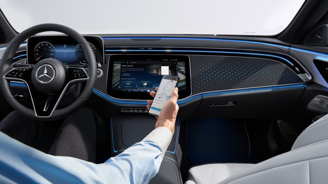 Detail aus dem Cockpit der neuen Mercedes E-Klasse in dem ein Mann mit Smartphone sitzt