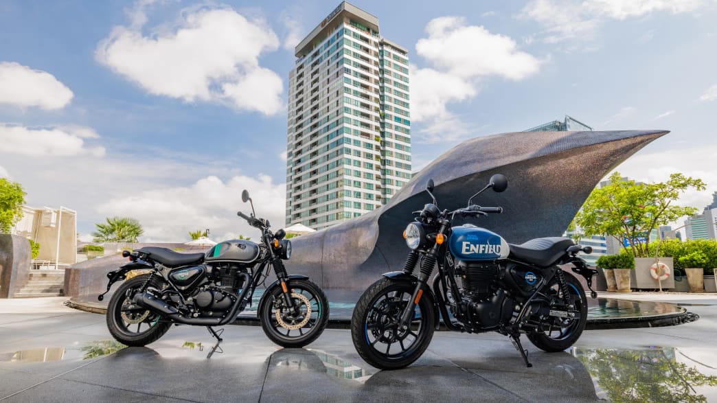 Zwei Motorräder vom Typ Royal Enfield 350 Hunter stehen vor einem Brunnen