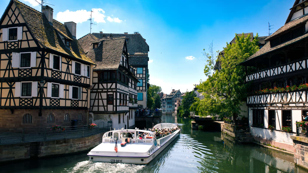 Ein Ausflugsboot auf dem Fluss Ill  der durch das Viertel Petit France in Straßburg fließt