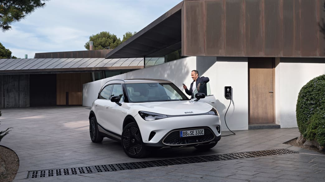Ein weisser Smart #1 SUV vor einer Garage an einer Wallbox