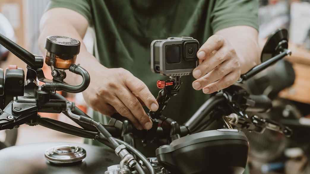 Ein Mann installliert eine GoPro auf sein Motorrad