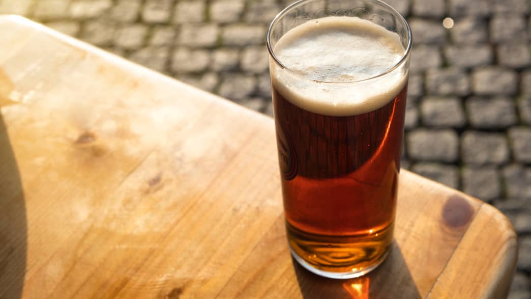 Ein Glas Altbier steht im Abendlicht auf einem Tisch in der Düsseldorfer Altstadt