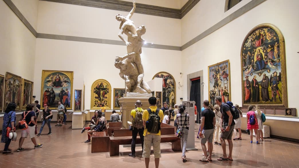 Besucher betrachten eine Statue in der Galleria dell Academia in Florenz