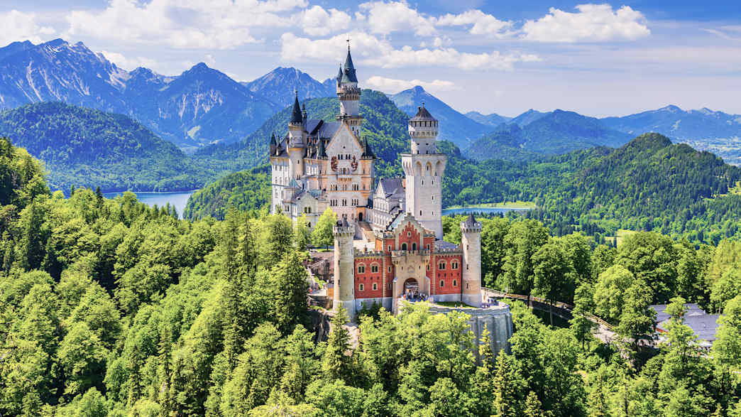 Außenansicht von Schloss Neuschwanstein mit den Alpen im Hintergrund
