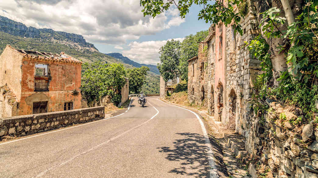Ein Motorradfahrer fährt auf einer Straße in Gairo auf Sardinien