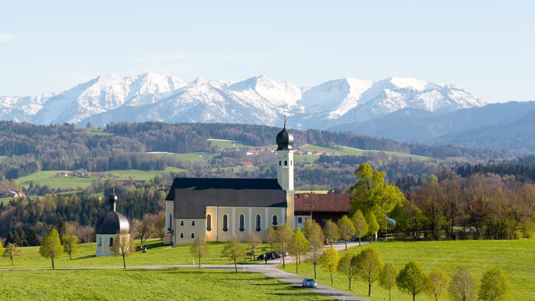 Die Wallfahrtskirche Wilparting vor der verschneiten Bergkulisse
