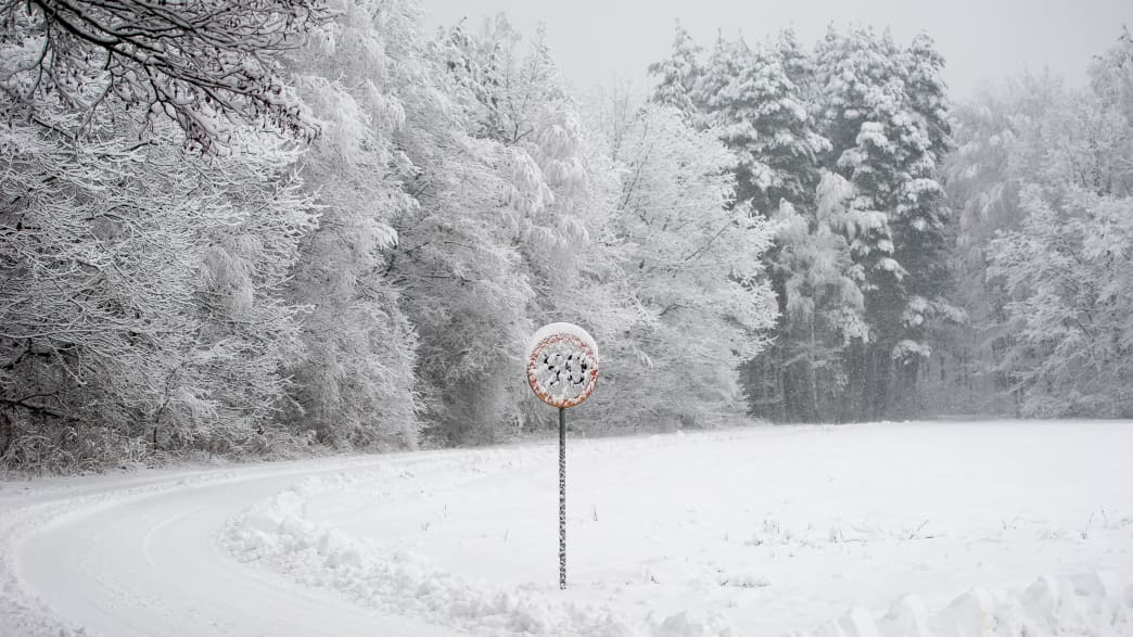 Schneebedeckte Landstraße mit verschneitem Verkehrsschild