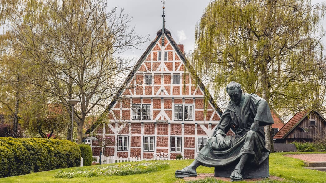 Fachwerkhaus und Statue des Priesters Heinrich von Carsten Eggers in Steinkirchen