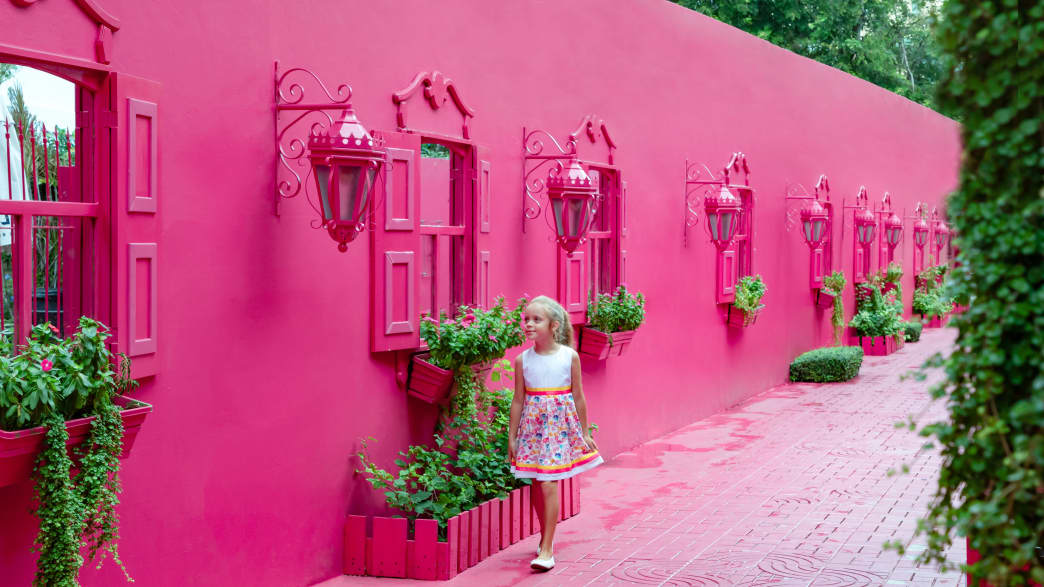 Ein kleines Mädchen läuft an einem pinken viktroianischen Haus entland in Puerto plata in der Domenikanischen Rebublick.