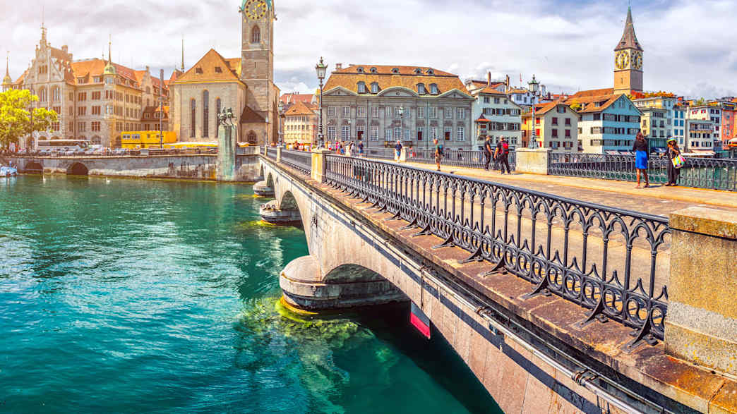 Blick auf die Altstadt von Zürich mit dem Fraumünster von der Brücke über die Limmat an einem sonnigen Tag