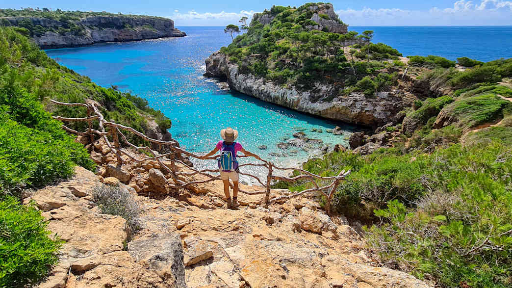 Eine Frau genießt den Ausblick auf die Bucht Cala des Moro auf Mallorca