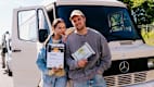 Ein Mann und eine Frau stehen lächelnd vor einem weißen Mercedes Wohnmobil. Sie halten eine Urkunde und eine Auszeichnung mit der Aufschrift "1. Platz ADAC Camper des Jahres".