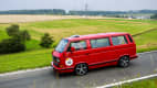 VW Multivan Last Limited Edition, Baujahr 1992: Dieser leuchtend rote Multivan fährt durch eine malerische Landschaft und zeigt den ikonischen Stil und die Vielseitigkeit dieses klassischen VW-Modells.
