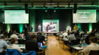 Professionelles Symposium mit Rednern und Teilnehmern in einem gut beleuchteten Konferenzraum, die über klimafreundliche Logistik diskutieren.