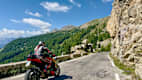 Ein Motorradfahrer fährt auf der kurvigen Südrampe des Col de la Cayolle durch die malerischen Täler der französischen Seealpen.