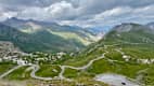 Serpentinenstraße am Col du Galibier in den französischen Seealpen mit grünen Tälern und bewölktem Himmel.