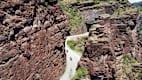 Luftaufnahme der Gorges de Daluis mit roten Felsen und einer kurvigen Straße, auf der Motorräder fahren.