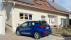 Ein blauer Opel Ampera-e läd an einem Privatgrundstück