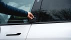 Hand hält Karte an den Türrahmen des Elektro-SUV Tesla Model Y um die Tür zu öffnen