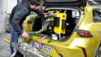 Ein Mitarbeiter aus Landsberg installiert Technik im Kofferraum eines Opels beim Eco Test 2023 im ADAC Technik Zentrum Landsberg