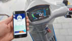 Ein Smartphone neben dem Display der Vespa Elletrica zeigt den Ladestand der Batterie an