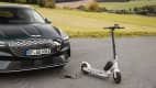 Der Genesis Electrified GV70 und ein Elektroroller stehen in einer Landschaft