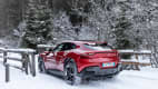 Rückansicht eines roten Ferrari Purosangue im winterlichen Wald