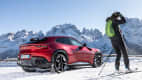 Ein roter Ferrari Purosangue vor verschneiter Bergkulisse