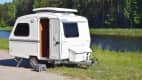 Der kleine Wohnwagen Niewiadow N126 ET von Blyss steht an einem Fluss