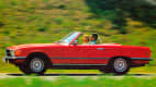 Roter Mercedes R107 fahrend auf einer Straße