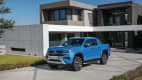 Der neue, blaue Pickup VW Amarok parkend vor einem Wohnhaus