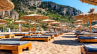 Liegestühle vor einer Felskulisse am Strand von Tsambika, auf der Insel Rhodos