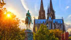 Der Kölner Dom im Sonnenuntergang mit einer Reiterstatue im Vordergrund